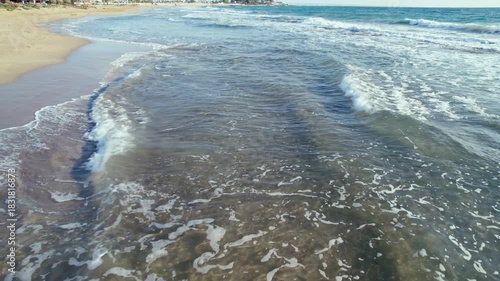 Filming the sea and beach above the water surface, shot from a drone