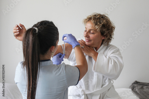 A wellness professional measures a client’s upper arm with a measuring tape in a clean, calm environment, assessing body size for health, fitness, or beauty purposes.