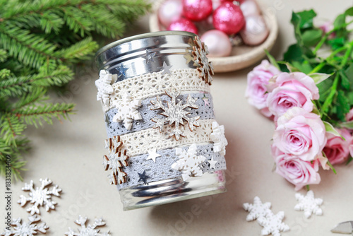 Florist at work: woman shows how to make modern Christmas decoration with fir, roses, pink baubles and decorative stars. The base is classic can. Step by step, complete tutorial.
