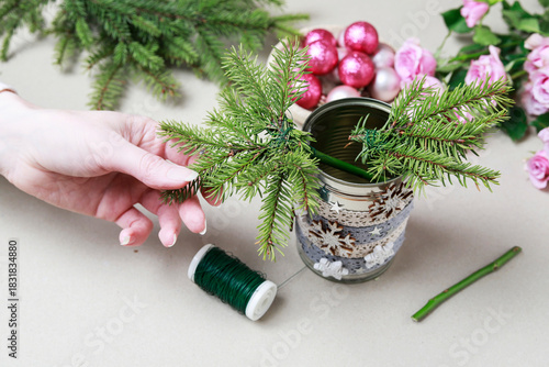 Florist at work: woman shows how to make modern Christmas decoration with fir, roses, pink baubles and decorative stars. The base is classic can. Step by step, complete tutorial.