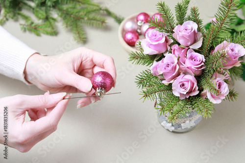 Florist at work: woman shows how to make modern Christmas decoration with fir, roses, pink baubles and decorative stars. The base is classic can. Step by step, complete tutorial.