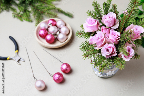 Florist at work: woman shows how to make modern Christmas decoration with fir, roses, pink baubles and decorative stars. The base is classic can. Step by step, complete tutorial.