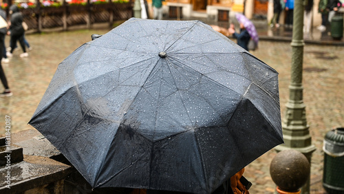 Umbrella covered with raindrops. A girl is holding an umbrella while it is raining in the city. Rainy day.