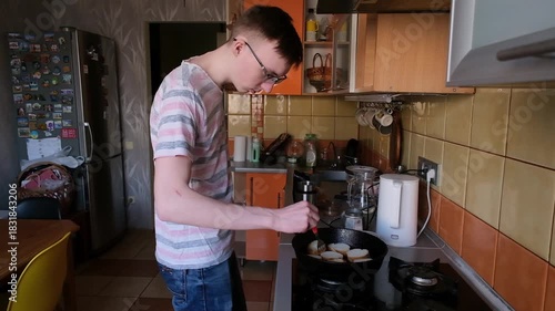 young man in the kitchen is preparing food for himself
