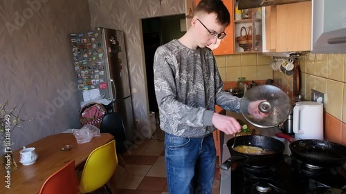 young man in the kitchen is preparing food for himself
