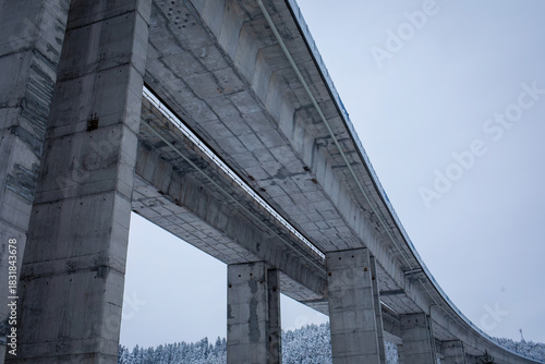 Winter Elevated Highway Bridge from Below .Massive Concrete Pillars in Snowy Landscape