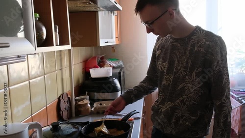 young man in the kitchen is preparing food for himself