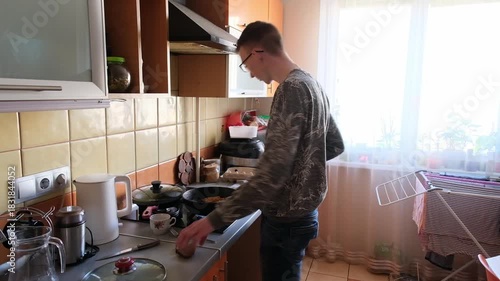 young man in the kitchen is preparing food for himself
