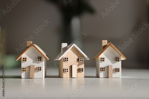 Three miniature wooden houses on table with soft light