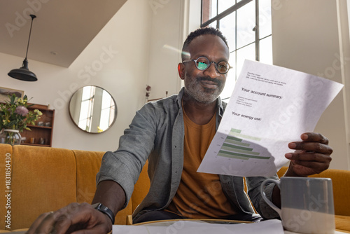Smiling man enjoys reviewing energy usage summary document