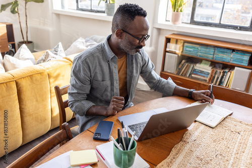 Focused individual working at home desk on laptop