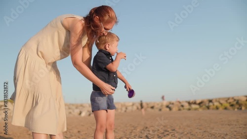 Mother helping son get dressed on the beach