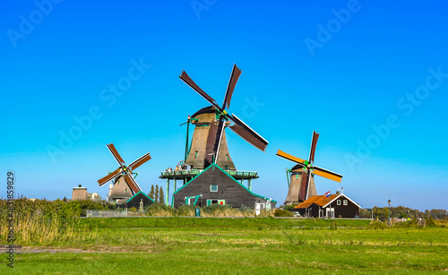 Classic Dutch countryside view with traditional windmills, green fields, and blue sky.