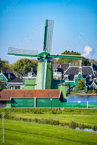 Beautiful traditional Dutch windmill painted in green, set against a vibrant blue sky.