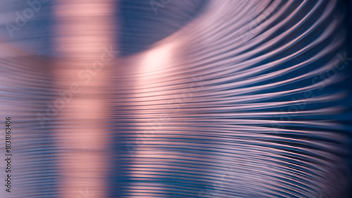 Abstract industrial metal background with blurred curved lines on blue. Shiny steel spiral spring texture with pink copper reflection for hardware manufacturing presentation. Photo