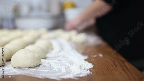 A female baker forms dough balls for buns. Macro photography.