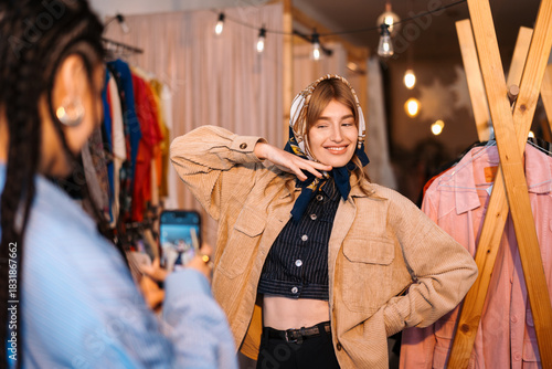 Stylish Young Woman Posing in Trendy Clothing Store with Friend Capturing Moment