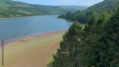 Aerial reveal of Talybont reservoir surrounded by forested hills in Wales