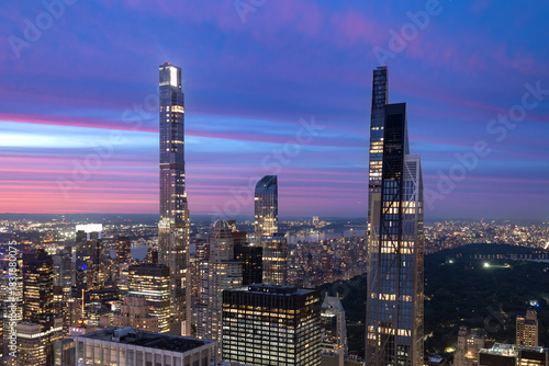 Photography The dramatic verticality of New York City Billionaires Row towers illuminated against a vibrant evening sky, with the urban sprawl extending below