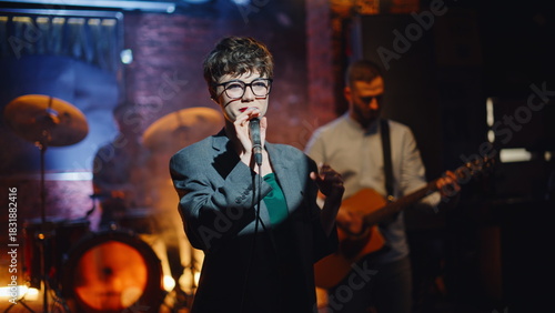 Artistic lady singing microphone at dark modern stage closeup. Beautiful woman