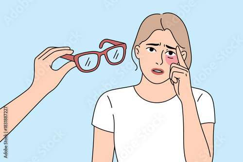 A person offers eyeglasses to a woman with a bruised eye, suggesting a need for vision correction or recovery from an injury.