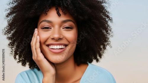 Joyful young Black woman with stunning curly hair smiles brightly, her radiant confidence and healthy skin reflecting authentic happiness and wellness