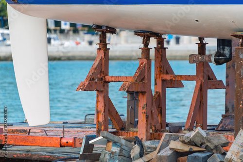 Boat hull maintenance with rusty stands in harbor setting
