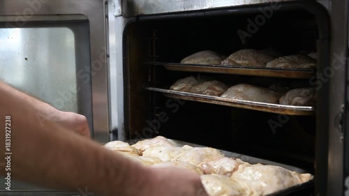 The cook inserts a baking tray with chicken legs into the combi steamer.