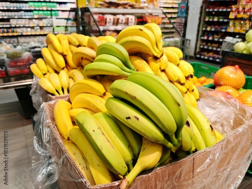Fresh Yellow Bananas Display in Grocery Store. Large pile of ripe yellow bananas in cardboard box at supermarket fruit section. Healthy eating, tropical fruit and shopping concept