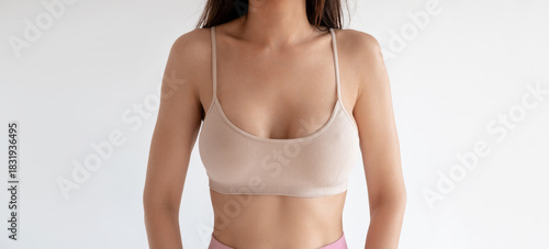 A female breast in beige ribbed sporty top closeup front view. Large boobs size after plastic surgery of implants. Supporting sportswear. Concept of cancer control. Toned breasts of an athletic woman.