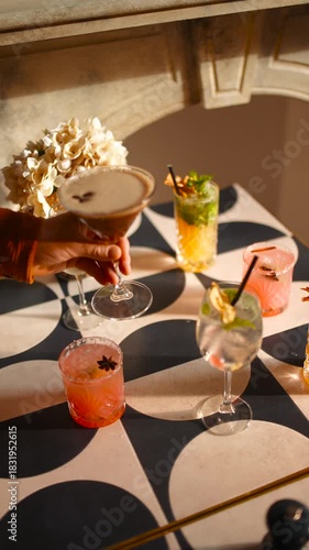A table with four drinks and a vase of flowers. The drinks are in different colored glasses and the flowers are in a vase. The table is set up for a party or gathering