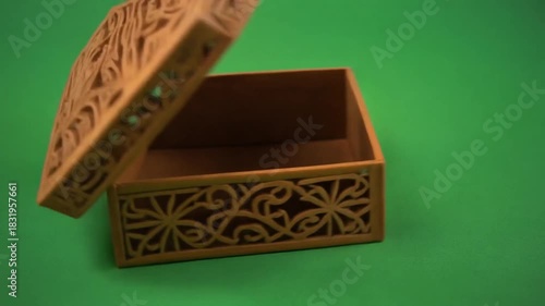Elegant Wooden Box with Intricate Floral Cutouts Against Green Backdrop