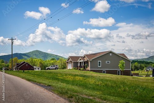 Countryside rural paved road leading to Lyndhurst, Virginia in summer season with houses and lush mountains