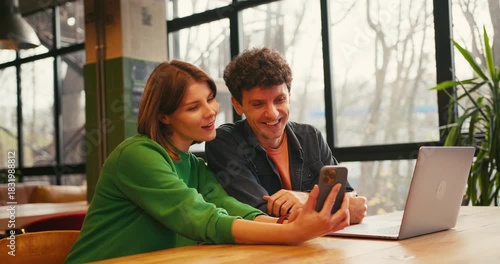 Couple, woman holding mobile phone using mobile app sitting in modern coworking