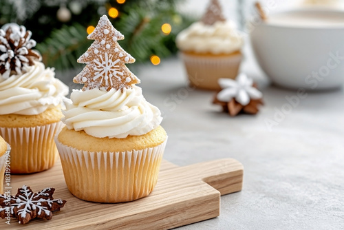 Vanilla christmas cupcake with white cream frosting topped with a gingerbread tree cookie and chocolate snowflake on a small wooden board. Concept of traditional holiday baking and elegant treat