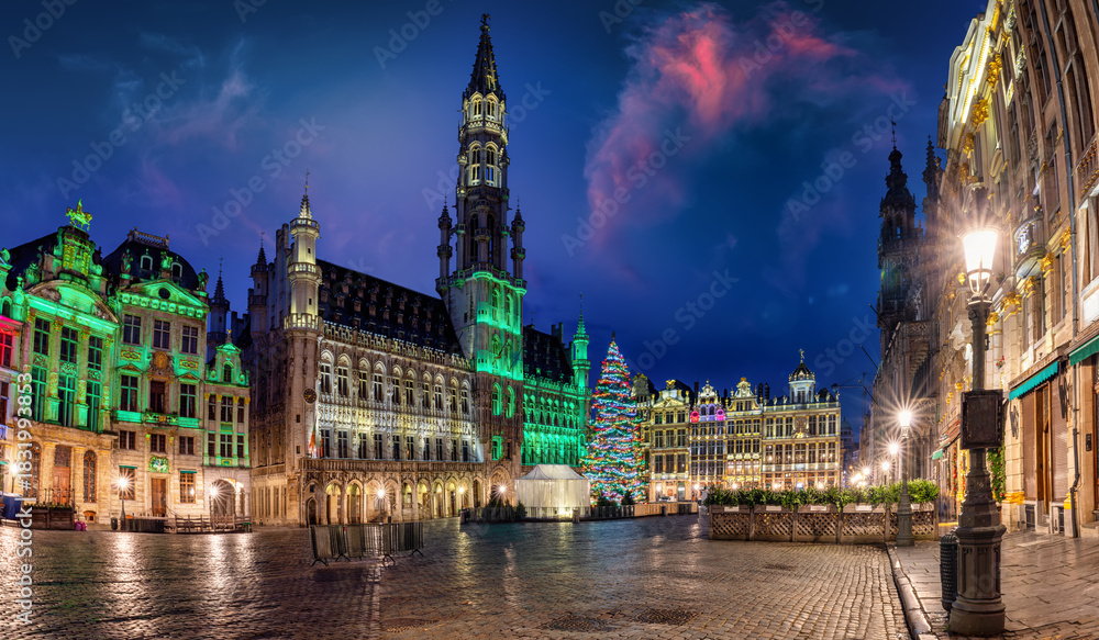 Naklejka premium Panoramic view of the illuminated Grande place with City Hall in brussels, Belgium, decorated for Christmas with tree and lights during dawn without people