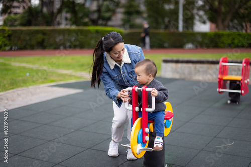 Baby playing on children rocking chair at playground