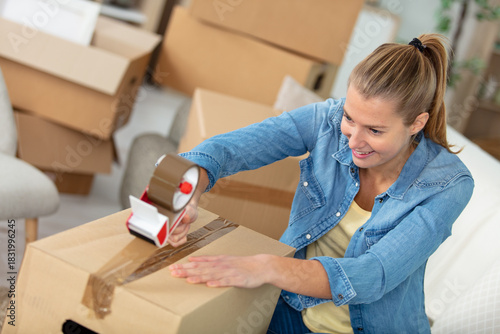 woman applying adhesive tape on cardboard box