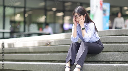 Businesswoman experiencing burnout sitting on stairs with head in hands.
