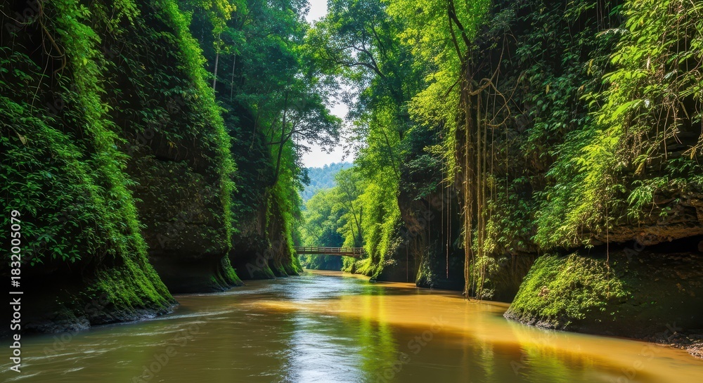 Fototapeta premium Deep tropical gorge with a serene river flowing through, lush green vegetation on the towering cliffs reflecting in the calm, sunlit water