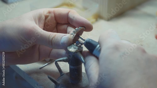 Dental technician polishing metal framework of dental bridge in laboratory prosthodontic production process.
