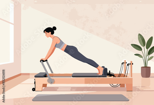 A woman in athletic wear is doing pilates on a reformer machine. A plant decorates the room