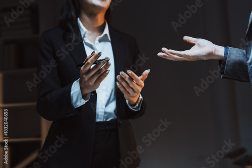 Business executive holding a pen and gesturing, having a serious discussion or negotiation with a colleague in an office setting