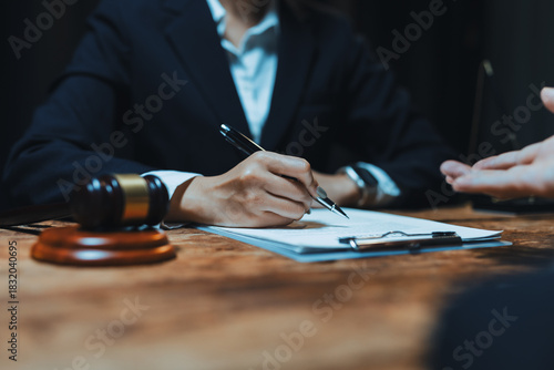 Legal professional in business suit signing a contract or agreement document on a clipboard during a consultation about judicial matters