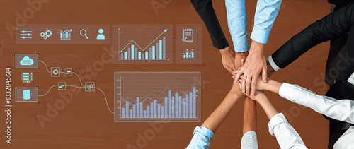 A collaborative team gathering with hands joined on a wooden table, showcasing data visualization, charts, and graphs for effective business analysis and strategy. Trope