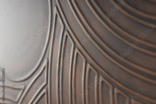 Abstract curved pattern on a brown background. Convex lines. The glare of light on the surface of the background. Abstract brown background with curved parallel lines and shadows.