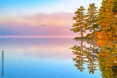 autumn mountain lake Barnum Pond in the Adirondacks of New York state reflecting with colorful morning fog at daybreak