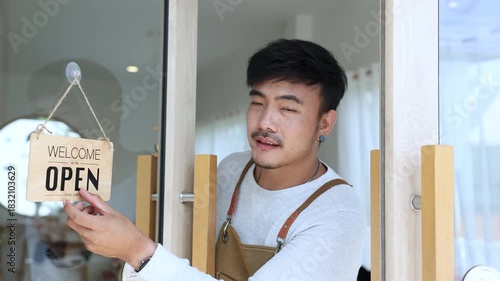 Small business coffee shop owner or employee, cafe entrepreneur preparing to open store, barista man showing open sign with friendly attitude, expressing working spirit, daily task welcoming customers
