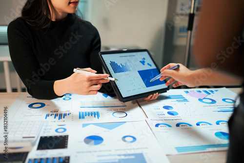 Business people analyzing financial data using tablet and papers