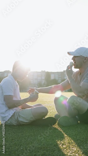 Father and son enjoying ice cream together outdoors on Father's Day. Vertical shot video.